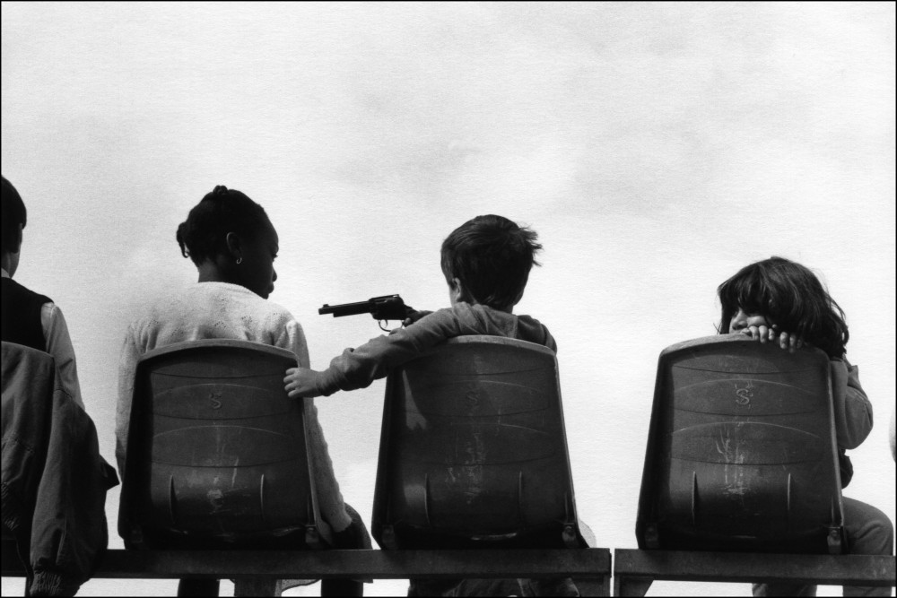 Enfants assis de dos et pistolet factice